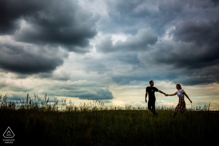 A couple walks together in Brno beneath a dramatic and dark sky in this engagement session by a Prague photographer