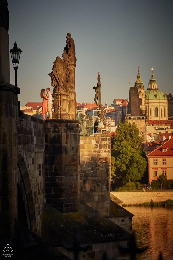 Engaged couple stand atop the Charles Bridge during their sunrise portrait session