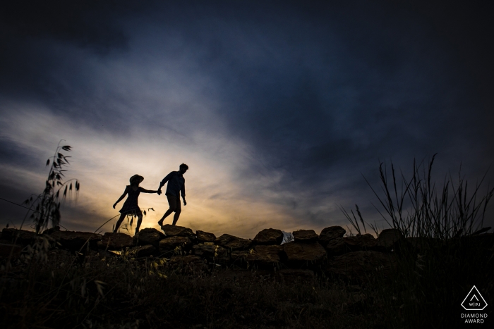 Silhouetted couple hold hands as they walk in Mersin, Turkey during their engagement shoot