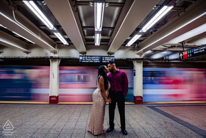 A subway train passes by as the engaged couple kiss during their engagement shoot at the Grand Central Station