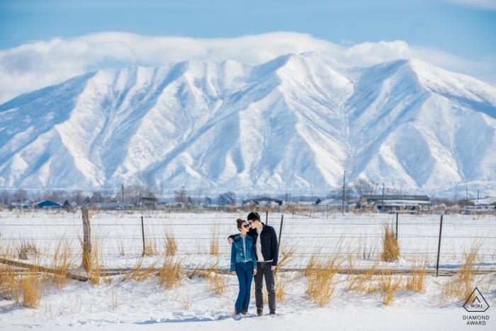 A couple poses in front of frozen mountains during their engagement photo by a Hangzhou City photographer A couple poses in front of frozen mountains in the United States during their engagement photo by a Hangzhou City photographer.