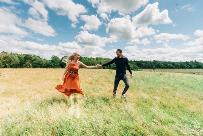 Una coppia si tiene per mano sotto un cielo blu in questo ritratto prewedding scattato da un fotografo di fidanzamento Overjissel