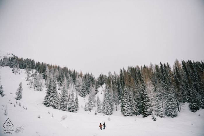 Nesta foto projetada por um fotógrafo de noivado de Apúlia, vemos o casal caminhando para as montanhas nevadas perto de Tretino