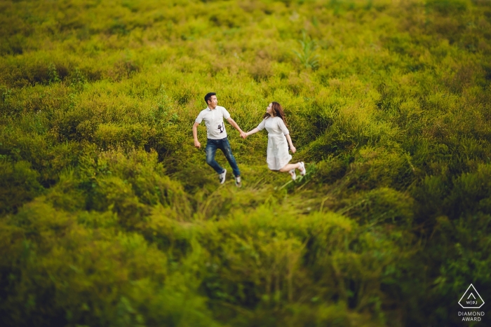 Grassland Engagement Session with couple jumping up in green fields