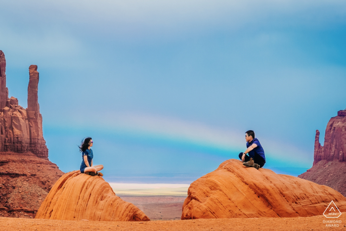 Foto door: <a href="https://www.wpja.com/photos/diamond-award-top-wedding-engagement-photographer/2523241"> Leon Wong - Hangzhou Verlovingsfotografie in Colorado | Het echtpaar bevindt zich in de Monument Valley, de regenboog verschijnt erachter.