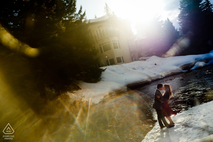 Vail, CO Engagement Shoot - In piedi vicino al fiume Eagle a Vail mentre gli ultimi frammenti di sole spruzzano attraverso gli alberi sempreverdi per questa sessione di fidanzamento invernale.