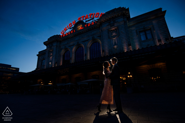 Photo par: <a href="https://www.wpja.com/photos/diamond-award-top-wedding-engagement-photographer/2536081"> Justin Edmonds - Denver Colorado Union Station, Denver, Colorado - Ce couple pose ensemble au crépuscule devant la station de Denver Union Station lors de la prise de photos de leur engagement.