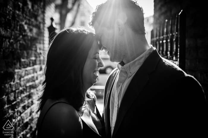 Photo by: <a href="https://www.wpja.com/photos/diamond-award-top-wedding-engagement-photographer/2539571">Allison Williams - Chicago Illinois Couple laughs together in a ray of sunlight during an engagement session in Roscoe Village in Chicago.