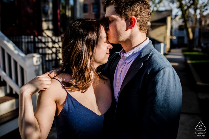 Photo by: <a href="https://www.wpja.com/photos/diamond-award-top-wedding-engagement-photographer/2539586">Allison Williams - Chicago Illinois Man kisses a woman's forehead during a Roscoe Village engagement shoot in Chicago.