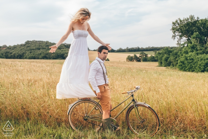 Gers, sul do fotógrafo do acoplamento de France - um par em uma bicicleta levanta durante a sessão do retrato do pre-casamento.