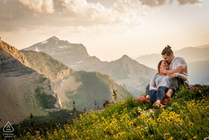 A couple sitting amongst the wildflowers at the Glacier National Park- Logans Pass