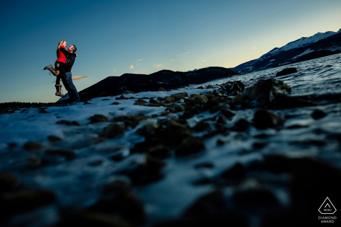 Photo: <a href="https://www.wpja.com/photos/diamond-award-top-wedding-engagement-photographer/2543655"> Trent Gillespie - Silverthorne Colorado Il soulève son fiancé par temps froid en se promenant près du réservoir de Dillon lors d'une séance de fiançailles.