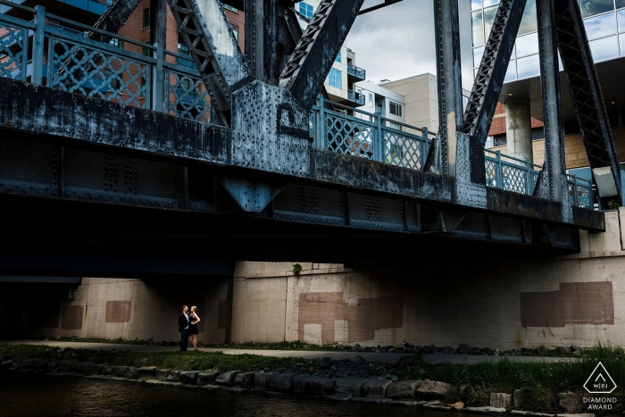 A couple stands under a pedestrian bridge in downtown Denver for their urban engagement session