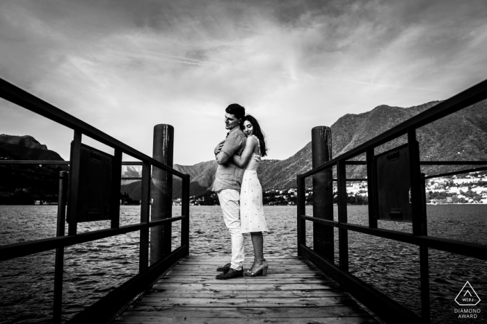 Como Lake pareja abrazándose en el muelle en el agua durante la sesión de fotos antes de la boda.