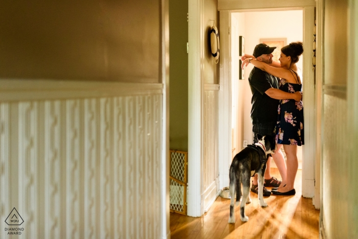 Coppia di fidanzati che abbracciano nella loro casa mentre il loro cane guarda in questo servizio fotografico di fidanzamento a Montreal