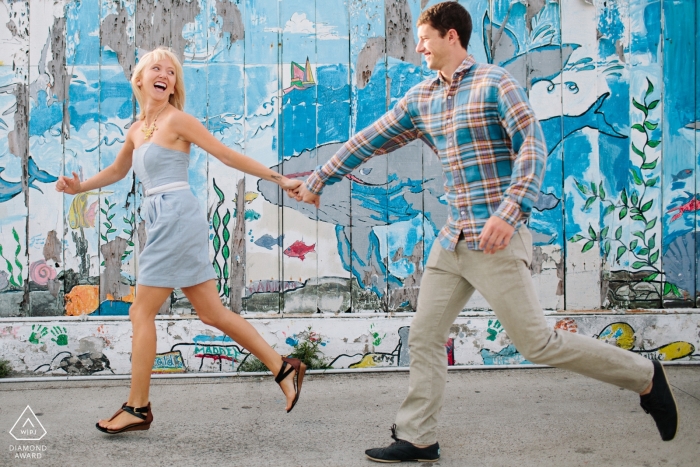 Foto: <a href="https://www.wpja.com/photos/diamond-award-top-wedding-engagement-photographer/2545187"> Ron Storer - Auburn Washington San Diego, Kalifornien Pre Hochzeitsfotografie | Porträt des Händchenhaltens eines Paares und Laufen auf der Straße nahe bei gemaltem Zeichen