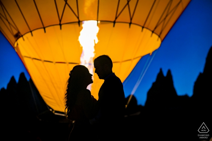 Cappadocia Turkey couple in front of the balloon fire during prewedding engagement portrait session at dusk