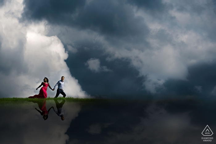 Pareja corriendo en las nubes sobre Edmonton, Alberta durante la sesión de retrato de compromiso.