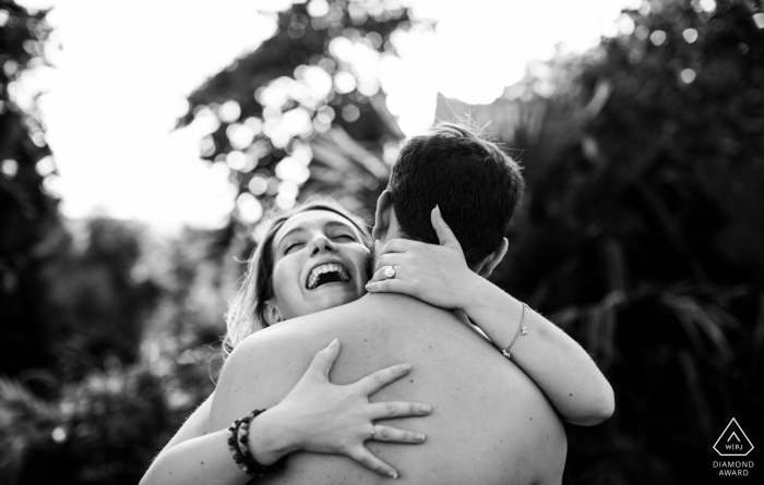 Casterat-Lectourois, Gers | Ein Mädchen, das während des Fotoshootings vor der Hochzeit im Arm ihres Freundes lacht