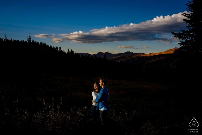 Portrait de fiançailles de Vail, CO | The Gore Range au coucher du soleil avec le couple regardant dans la lumière.