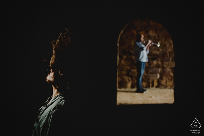 Engagement Photography for Zamora - Image contains: couple, arch, stone, hair, light, shadows, trumpet, horn