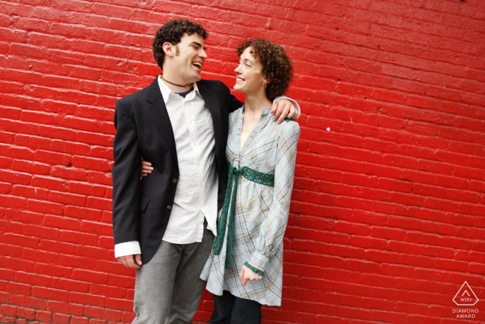 Fotografia de noivado por Little Five Points, Atlanta | Casal rindo juntos em frente a parede vermelha