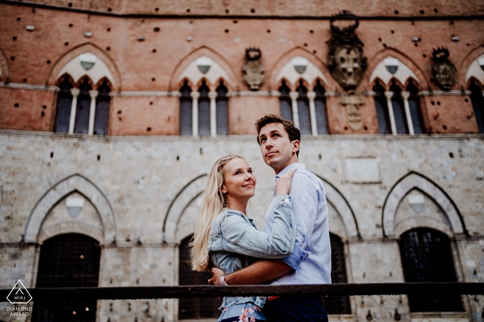 Engagement Photographer for Siena, Piazza del Campo - Portrait contains: couple, embrace, public square, building