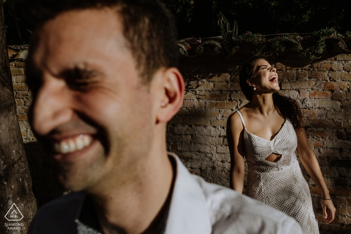 Engagement Photography for O Butia - Porto Alegre - Rio Grande do Sul - Image contains: laughing, portrait, brick, wall, couple