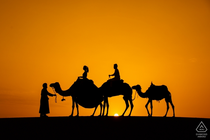 Engagement Portrait from Morocco Sahara Desert  - Image contains: camels, couple, desert, sunset, silhouette