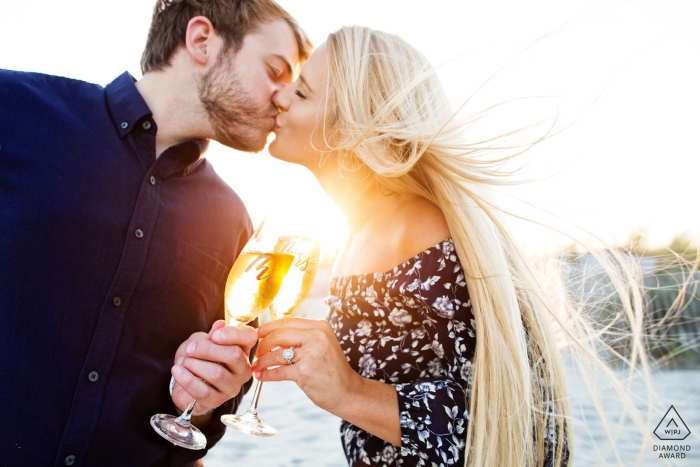 Photo by: <a href="https://www.wpja.com/photos/diamond-award-top-wedding-engagement-photographer/2551827">Michelle Arlotta - Milford New Jersey Engagement Photographer for Avalon, New Jersey Beach - Image contains: couple, kiss, beach, wine glasses, toast, engaged