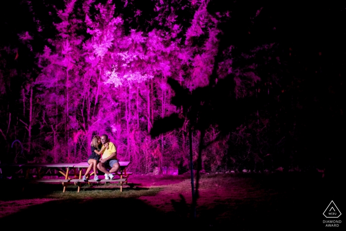 Photo by: <a href="https://www.wpja.com/photos/diamond-award-top-wedding-engagement-photographer/2551956">Orçun Yalçın - Ankara Ankara Güzelçamlı Kuşadası, Turkey Engagement Photography | Couple sitting on a picnic table looking each other and laughing and the background is highlighted with purple colour