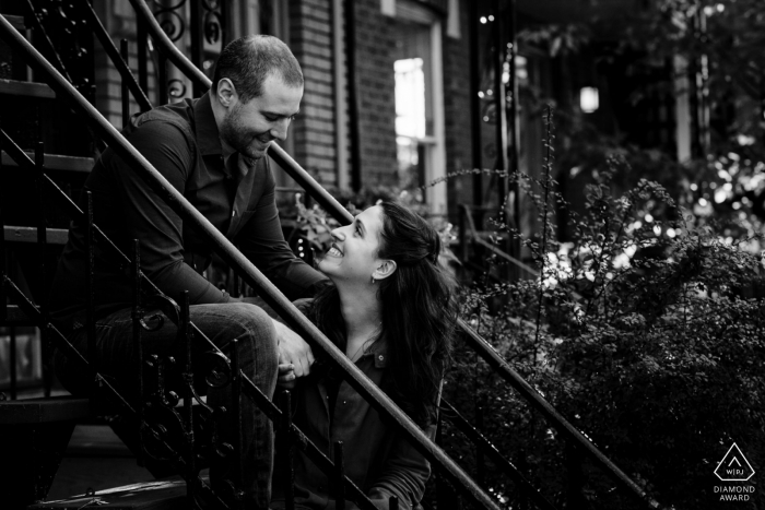 Villeray, Montreal, Canada — Black and white engagement photo of couple sitting on stairs in front of their Montreal apartment 