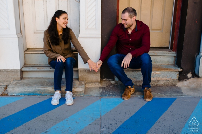 Montreal, Quebec Engagement photo of couple holding hands and sitting on front steps 