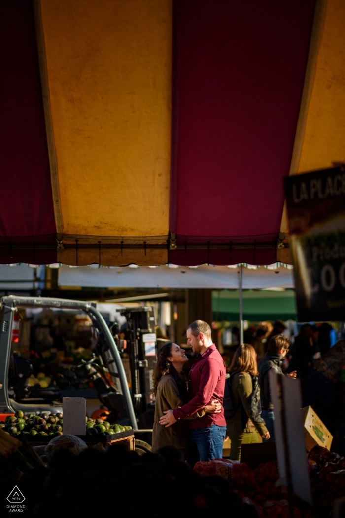 Mercato Jean-Talon a Montreal, Quebec foto di fidanzamento di coppia che si abbraccia, incorniciata dalle tende del mercato degli agricoltori