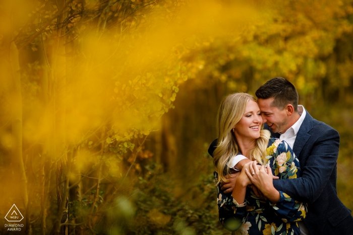 Breckenridge couple loving on each other in a grove of yellow aspen trees. 