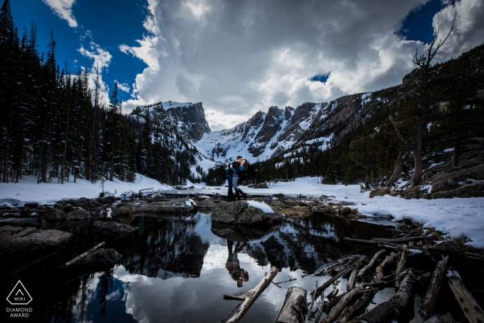 Estes Park Pareja en las montañas rocosas durante la sesión de compromiso bajo nubes y cielos azules