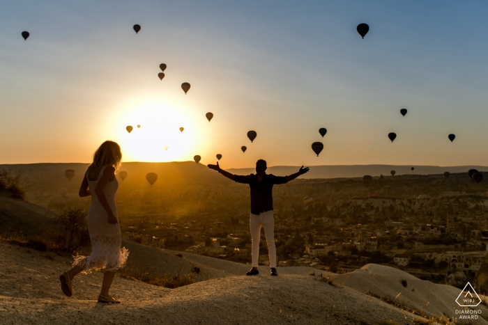 Foto: <a href="https://www.wpja.com/photos/diamond-award-top-wedding-engagement-photographer/2559971"> Orçun Yalçın - Ankara Ankara Kappadokien, Türkei Engagement Portrait Session | Das Mädchen, das zum Mann zur Sonnenaufgangzeit und zu den Heißluftballonen und am Hintergrund läuft