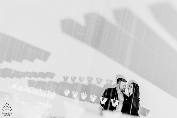 Photo by: <a href="https://www.wpja.com/photos/diamond-award-top-wedding-engagement-photographer/2560134">Brittany Diliberto - Arlington Virginia A couple laughs together in a hanging prisim art installation. Engagement photography at the National Gallery of Art East Wing