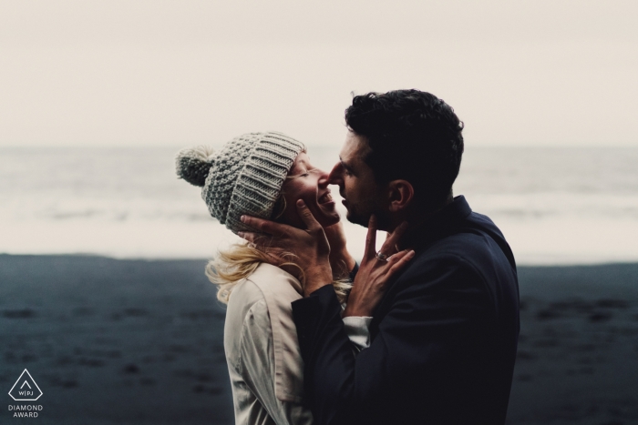 Couple sur la plage de sable noir s'embrasser pendant la séance de portrait d'engagement en Islande Couple sur la plage de sable noir s'embrasser pendant la séance de portrait d'engagement en Islande