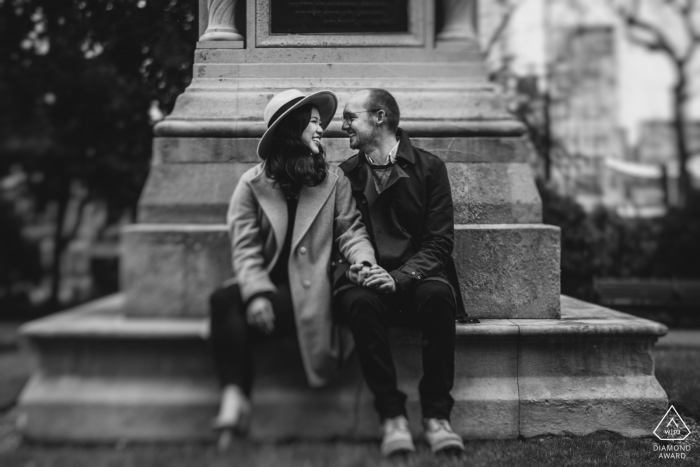 London Couple sat on bench while posing for their engagement pictures.