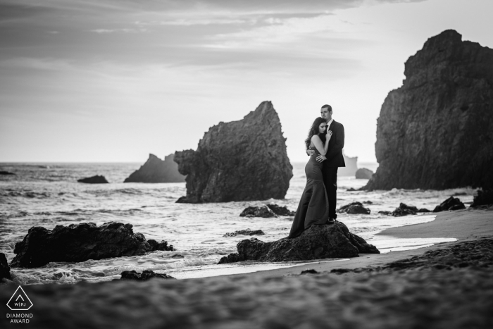 El Matador Beach Malibu CA Beach retrato de una pareja de pie sobre una roca en el agua.