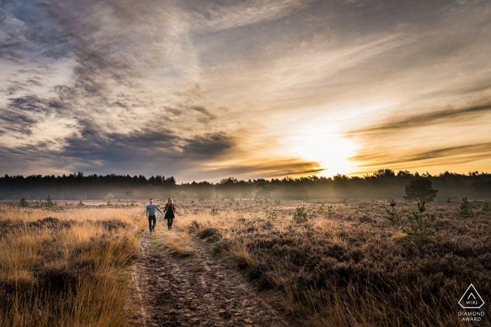 Coppia di fidanzati che cammina sulla brughiera durante il servizio fotografico a Rucphense Heide, Rucphen