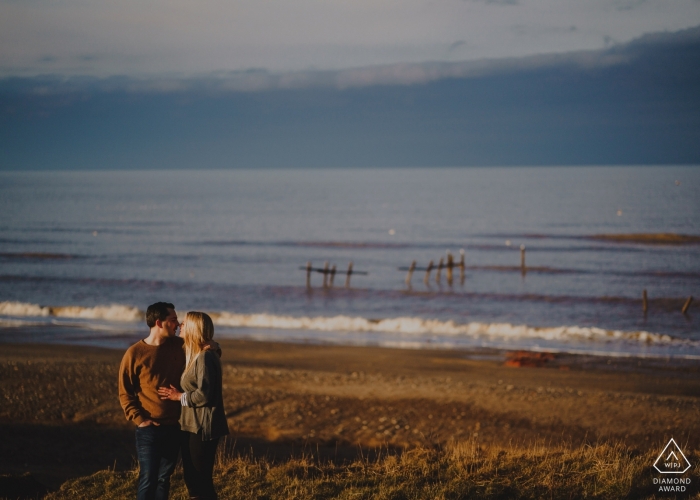Photo by: <a href="https://www.wpja.com/photos/diamond-award-top-wedding-engagement-photographer/2565319">Rob Dodsworth - Norwich Norfolk Beach Engagement Photography - A couple embrace at last light on the cliffs at Happisburgh in Norfolk, UK