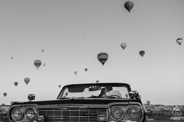 Cappadocia, Turchia Ritratti di fidanzamento di primo mattino con mongolfiere e auto d'epoca convertibile