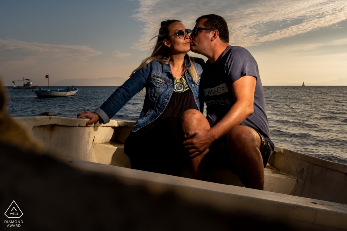 Badavut, Ayvalık, Balıkesir Ein Paar sitzt auf einem Boot und küsst sich während einer Verlobungsfotosession.