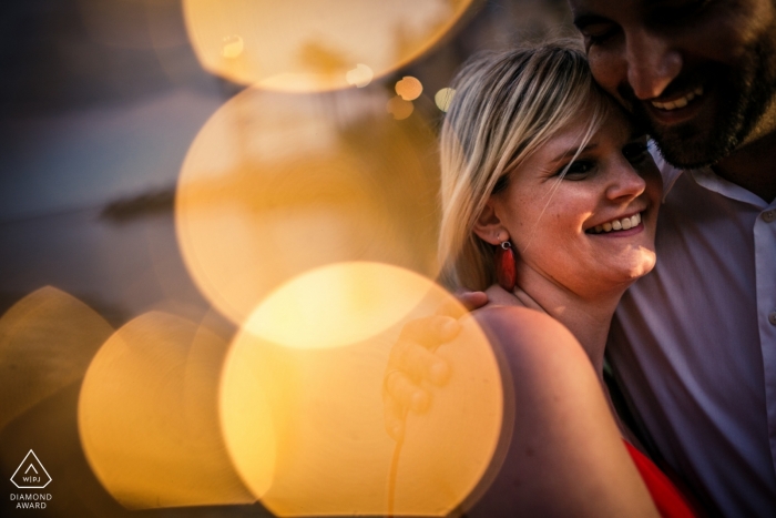 Cascais, PT Engagement Photo Session - Portrait contains: points, bokeh, light, hug, smile, red dress