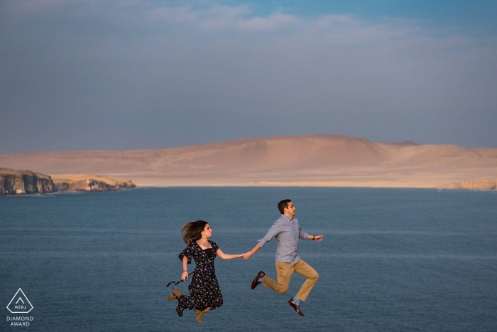 Fotografia di fidanzamento di Paracas Perù - Ritratto contiene: Coppia che salta di fronte all'oceano e al deserto