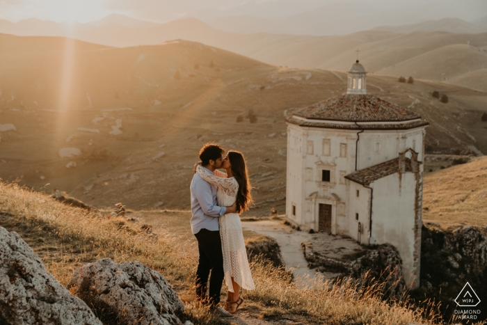 Calascio Fortress, Italy Engagement Photo Session - Image contains: afternoon, couple, kissing, mountains