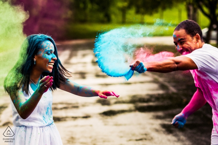 Alemania Pareja arrojándose polvo el uno al otro | Sesión de fotos de compromiso - Retrato contiene: verde, azul, rosa, riendo, divertido, juntos, sonrisas