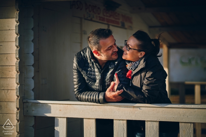 Porto Cesareo Engagement Photography Session - Image contains: railing, leaning, black, jackets, holding, sunlight